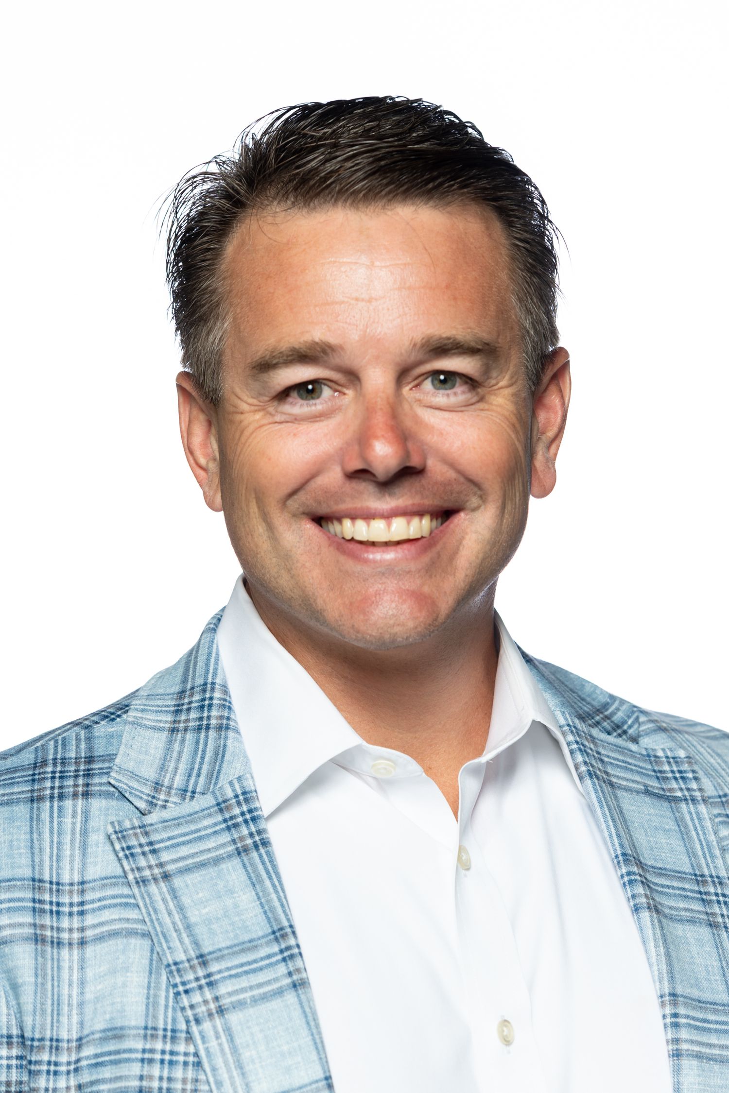 Professional man in blue plaid suit with arms crossed smiling confidently outdoors near columns.