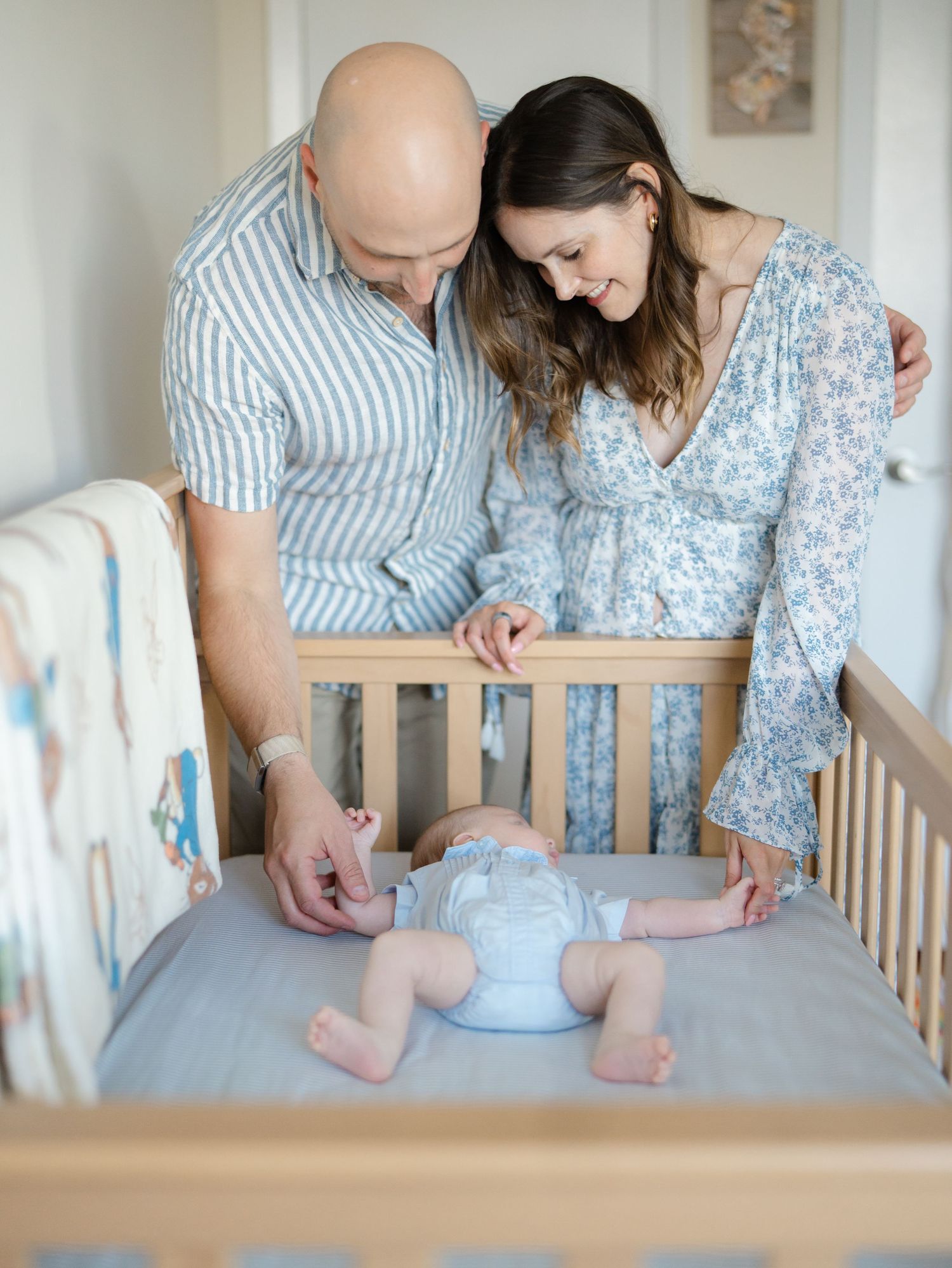 New parents look over newborn's crib and grabs his hands during a photo session in belmar nj.