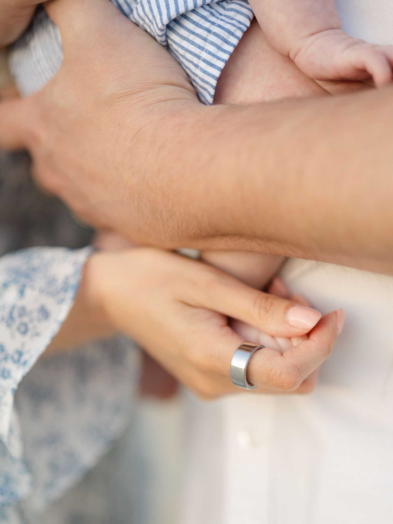 Close up of parents hands holding their newborn baby close.