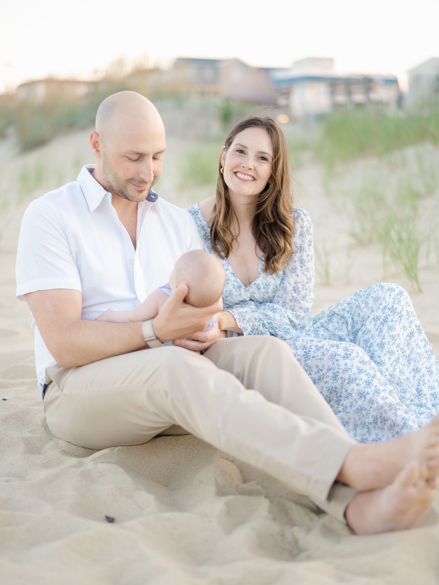 Mother and father sitting on the sand with baby in their arms in near the 8th ave playground.