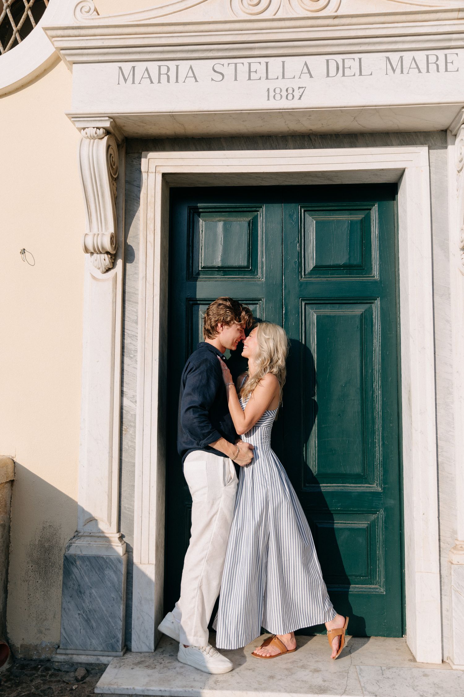 A couple kissing in front of green and marble door in Sorrento