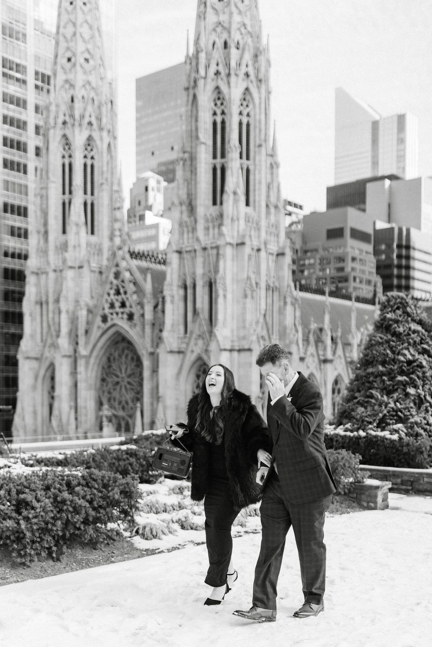 Couple laughing in front of St. Patrick's Cathedral in NYC, black and white engagement photo.