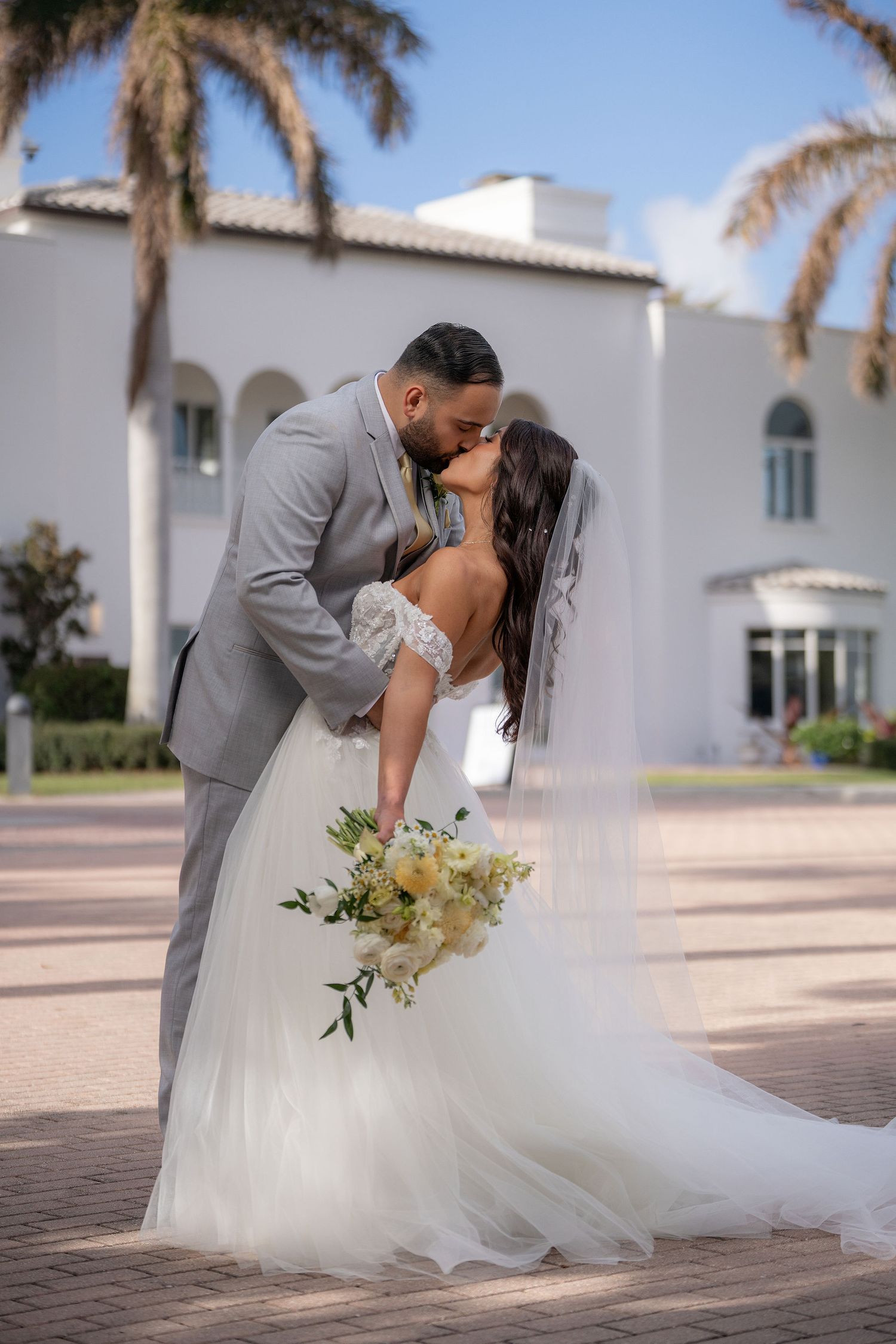 Bride and groom kissing on the pavers with the arches of the Mansion at Tuckahoe behind them