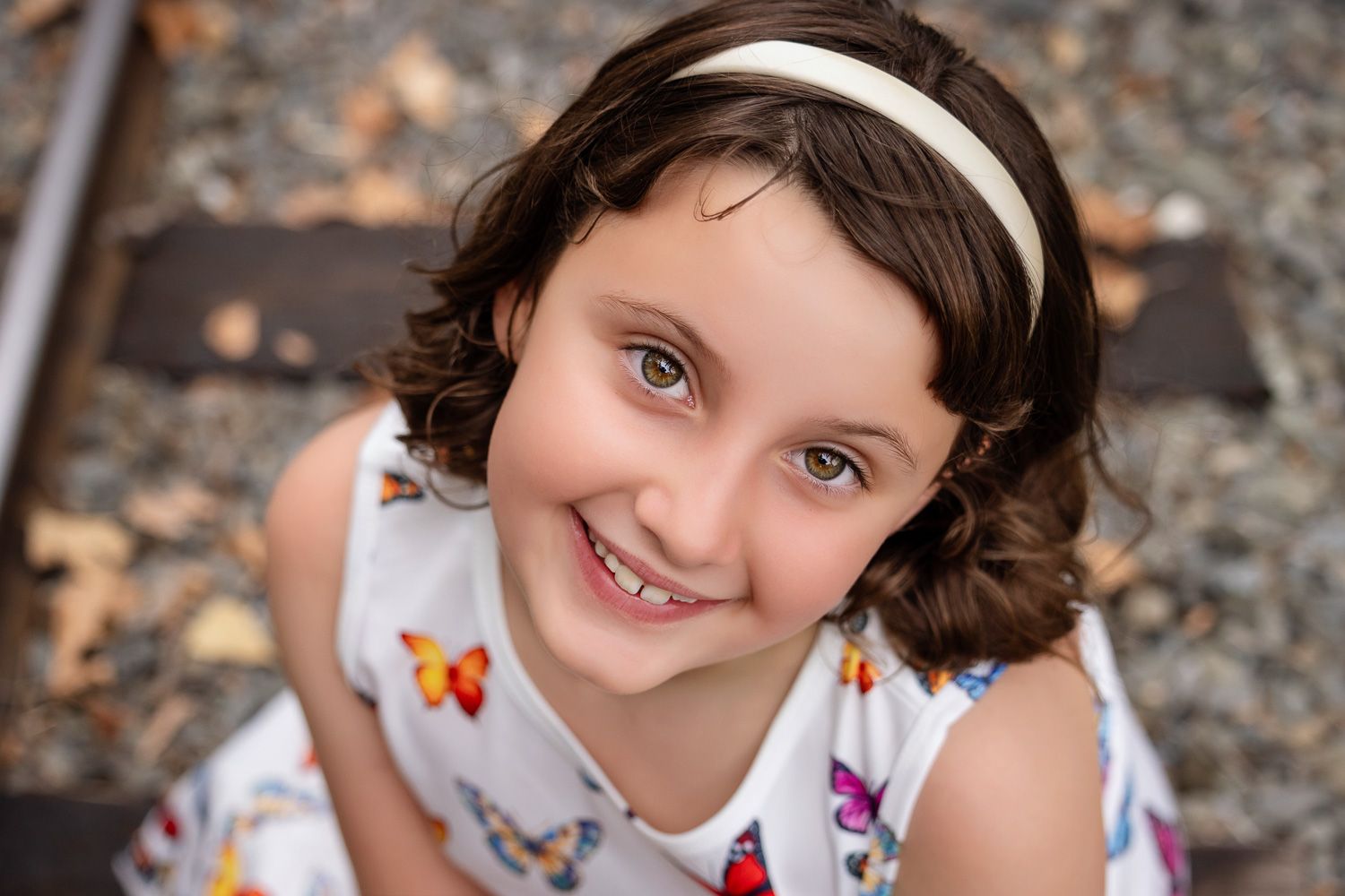 A portrait of a smiling girl sitting on train tracks