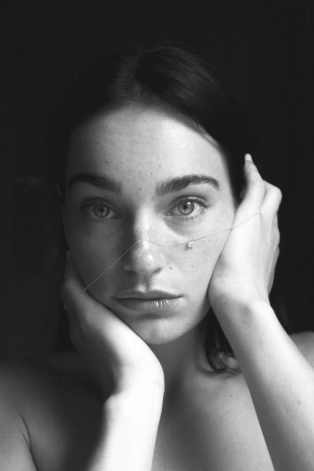 Emotive black and white portrait with hands framing face.