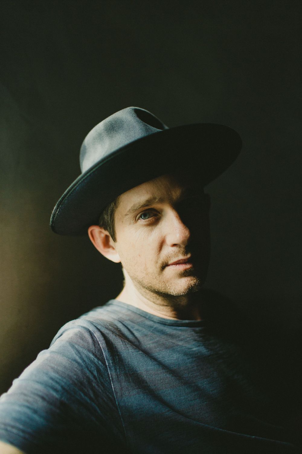 Portrait of someone wearing a dark hat against a muted background.