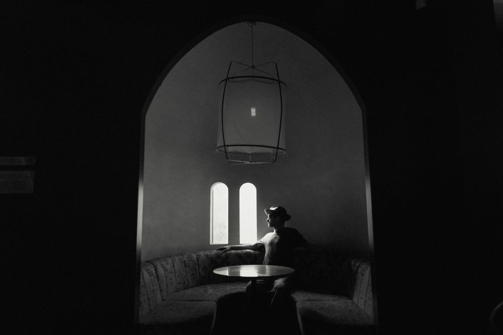 Moody black and white interior with arched windows and hanging lantern.
