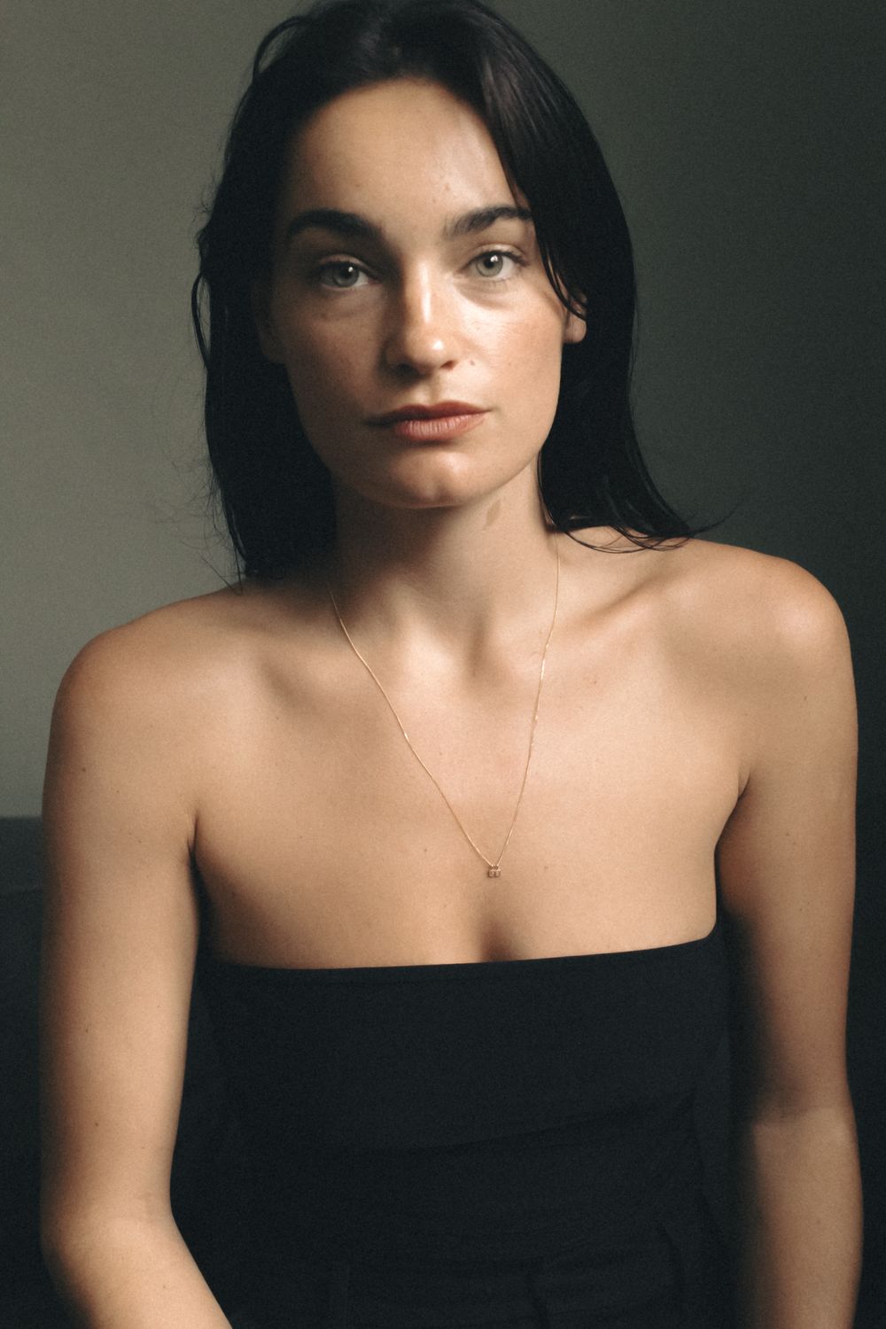 Elegant portrait with minimalist styling against neutral background.