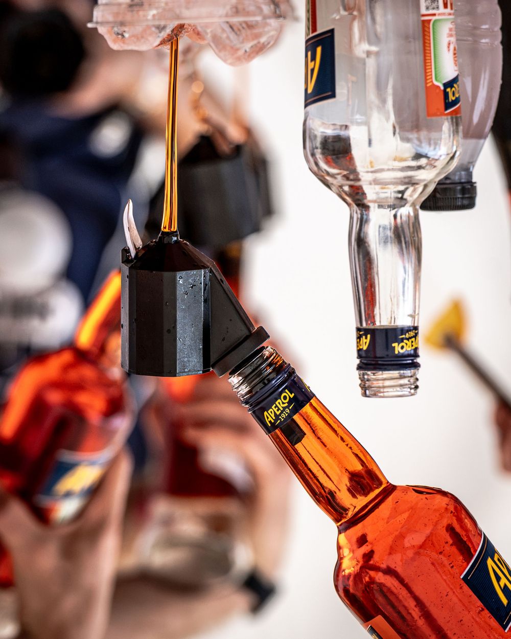 Aperol spirit bottles mounted upside down on a bar dispenser system, showcasing amber liquor in a professional bar setting.