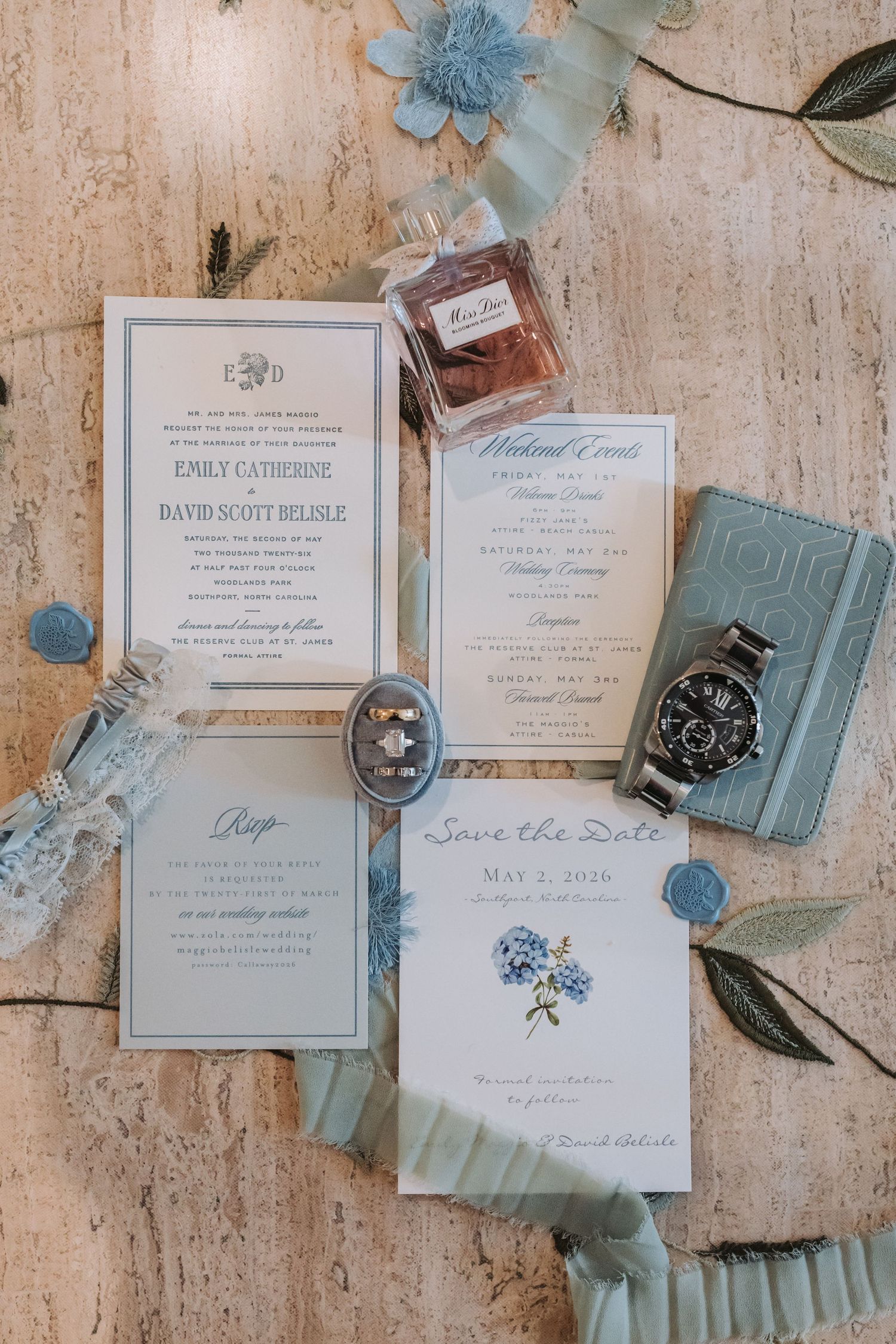 Elegant blue and white wedding stationery suite with save the date, invitations, watch, perfume, and wax seals.