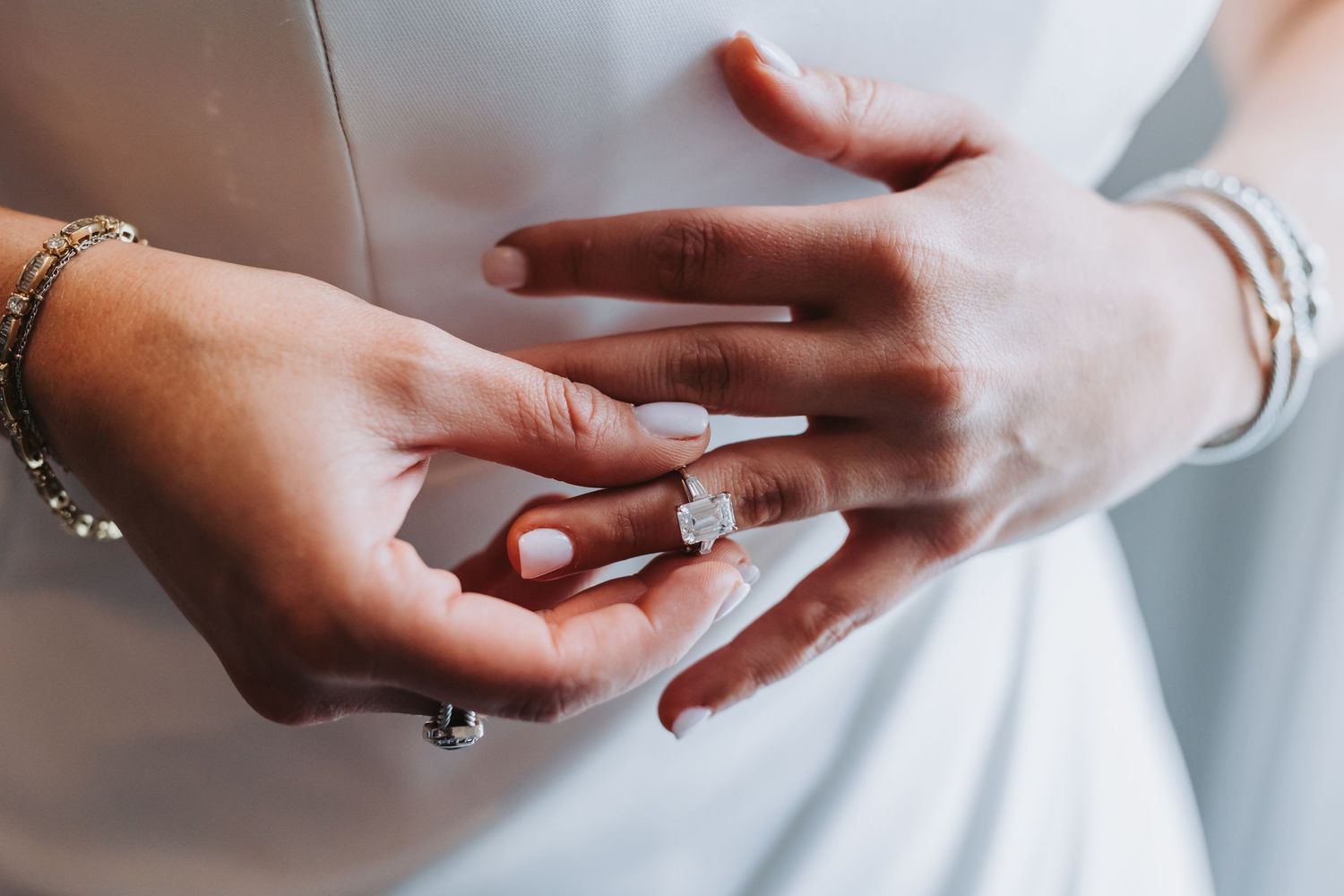 Close-up of bride wearing stunning diamond engagement ring with elegant bracelets on wedding day.