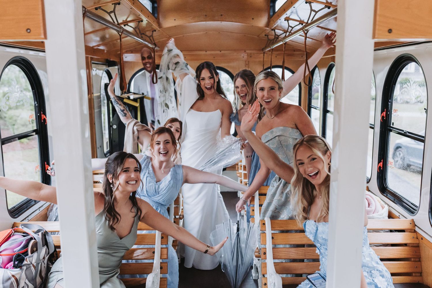 Bride and bridesmaids in blue dresses celebrating joyfully inside a vintage wedding trolley.