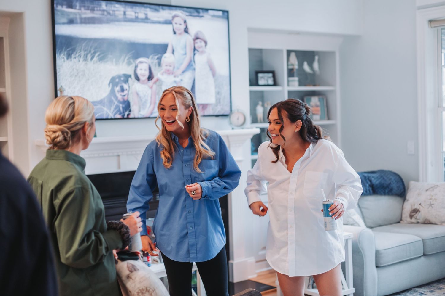 Women laughing and chatting in a bright living room during bridal party getting ready.
