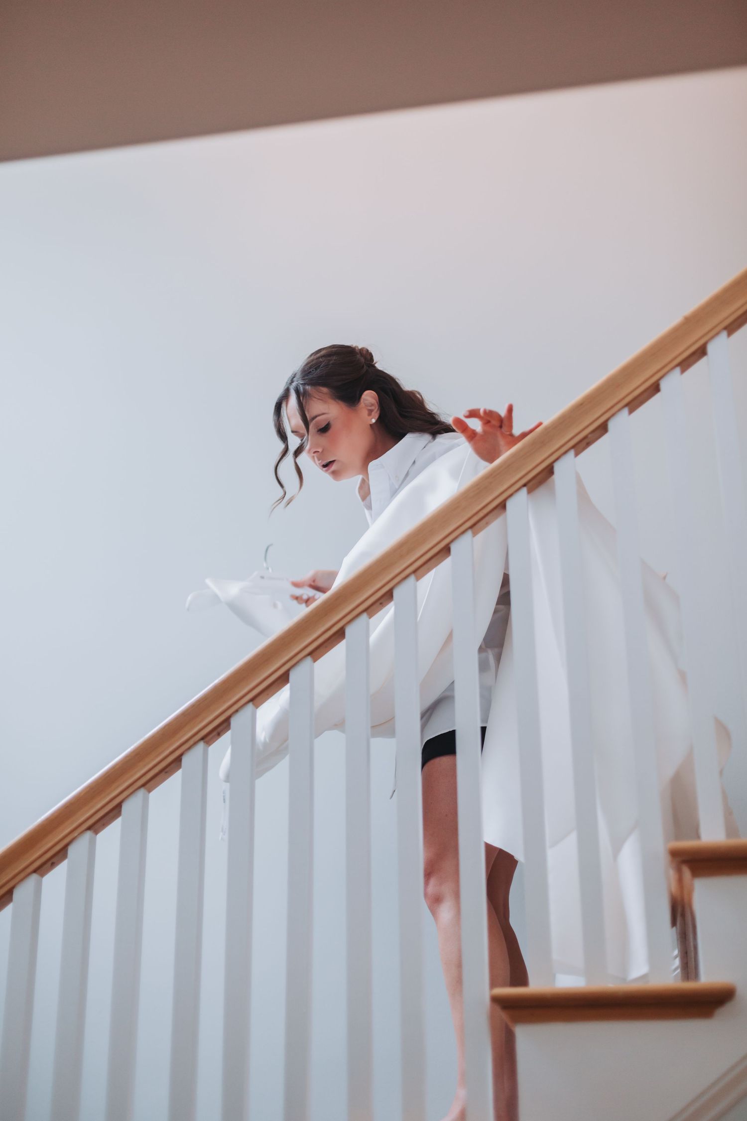 Bride in white robe reading a note on a staircase before her wedding ceremony.