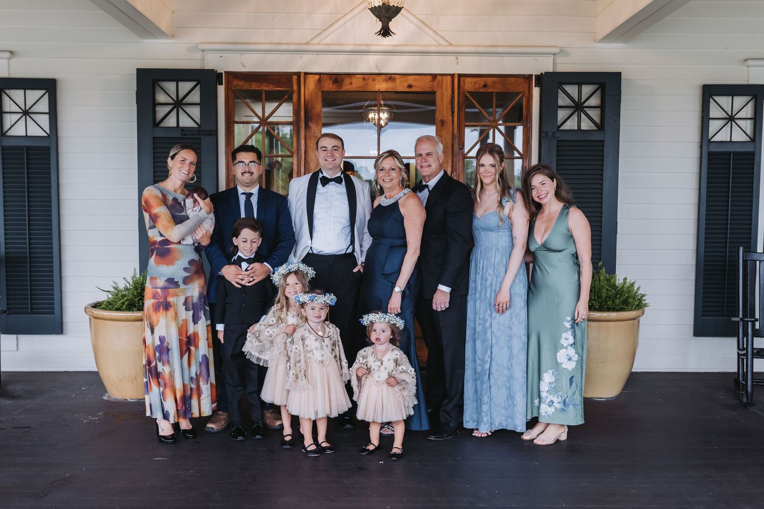 Wedding family group photo with couple, children in flower girl dresses, and relatives.