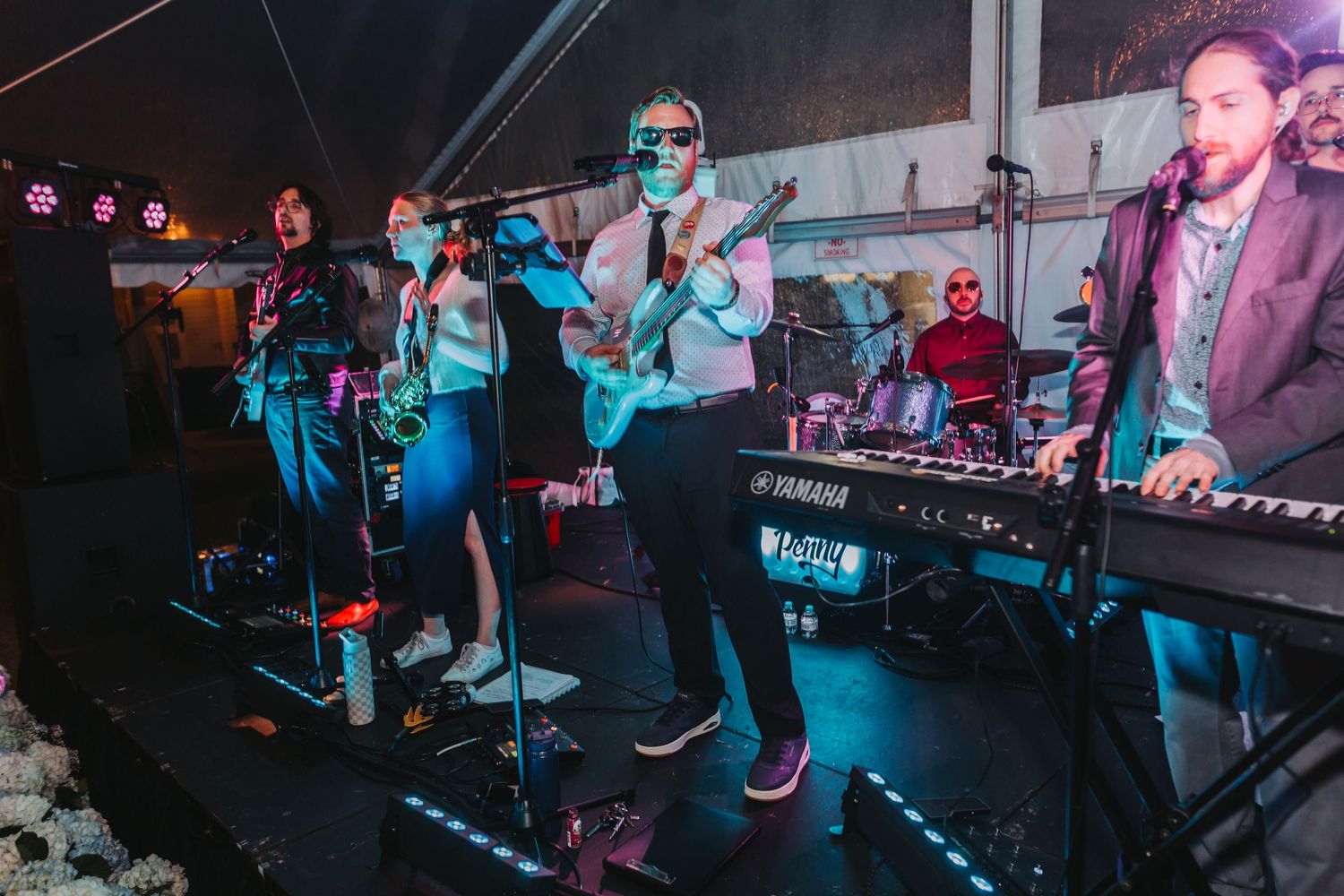 Live wedding band performs energetically on stage under colorful lights at festive evening reception.