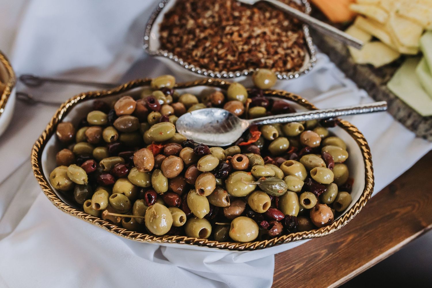 Close-up of a decorative bowl filled with mixed marinated olives served at a wedding reception.
