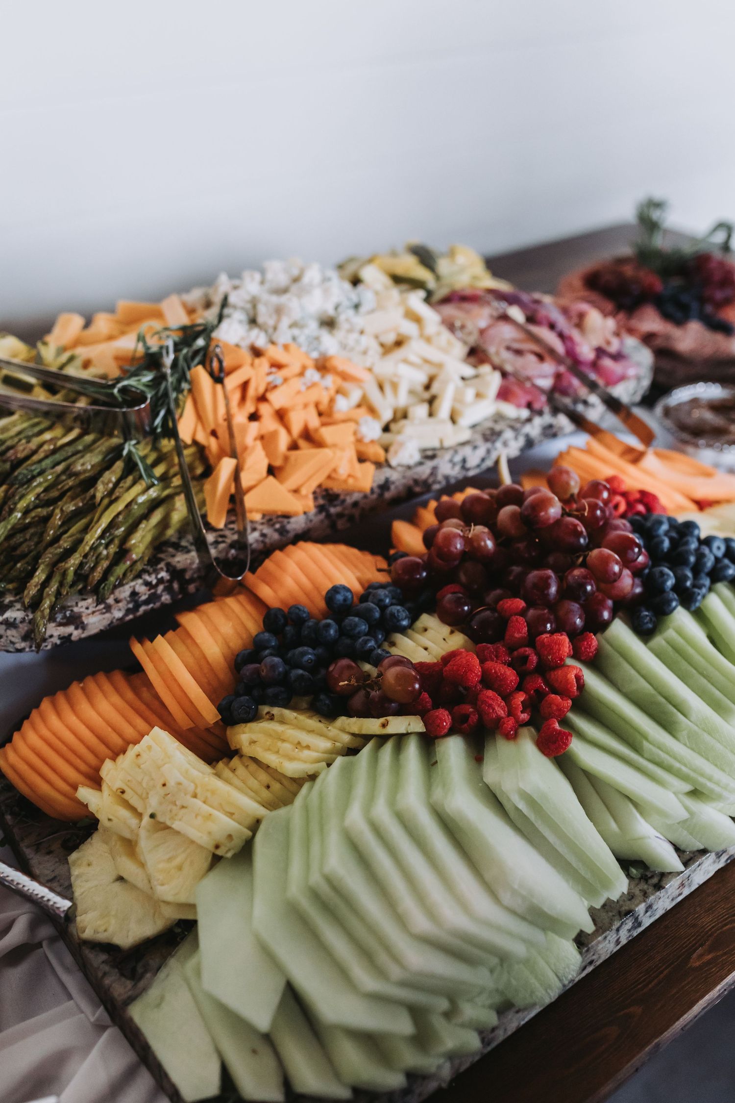 Elegant wedding charcuterie board with fresh fruits, vegetables, cheeses, and meats artfully arranged.