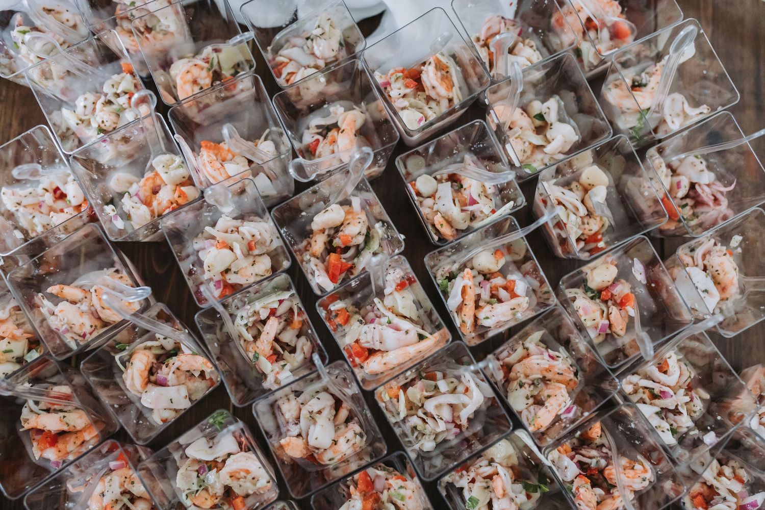 Overhead view of fresh seafood portions served in clear plastic containers at a catered event.