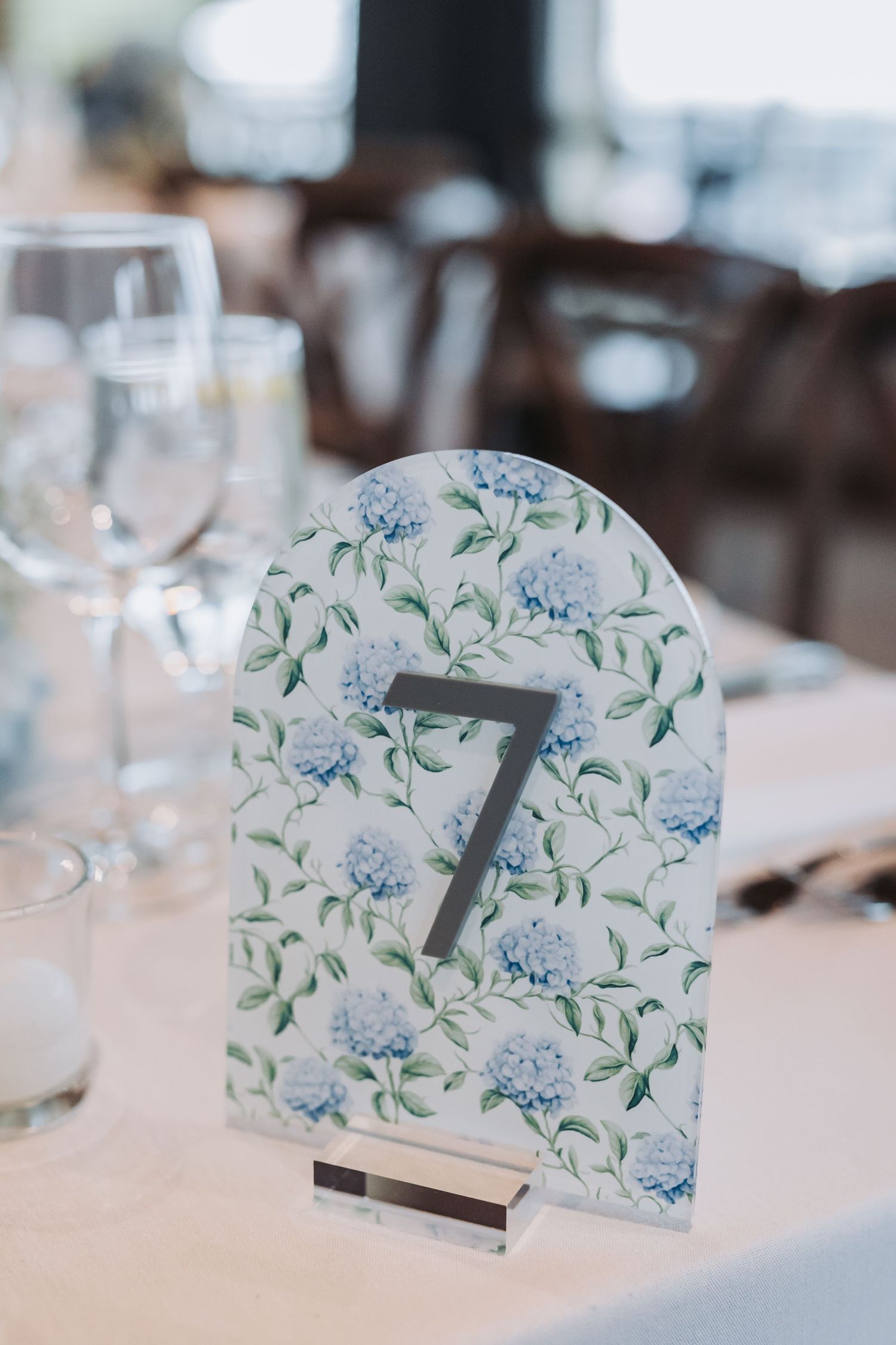 Floral table number seven card with blue hydrangeas displayed at a wedding reception table.