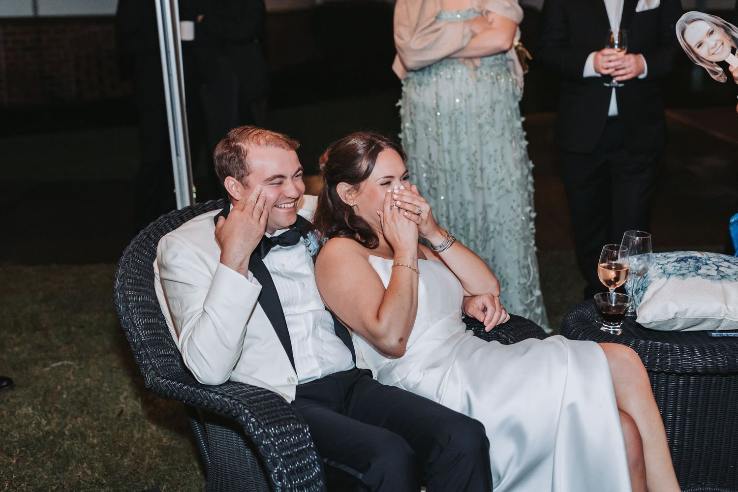 Bride and groom laughing emotionally while seated together during heartfelt wedding reception speeches.