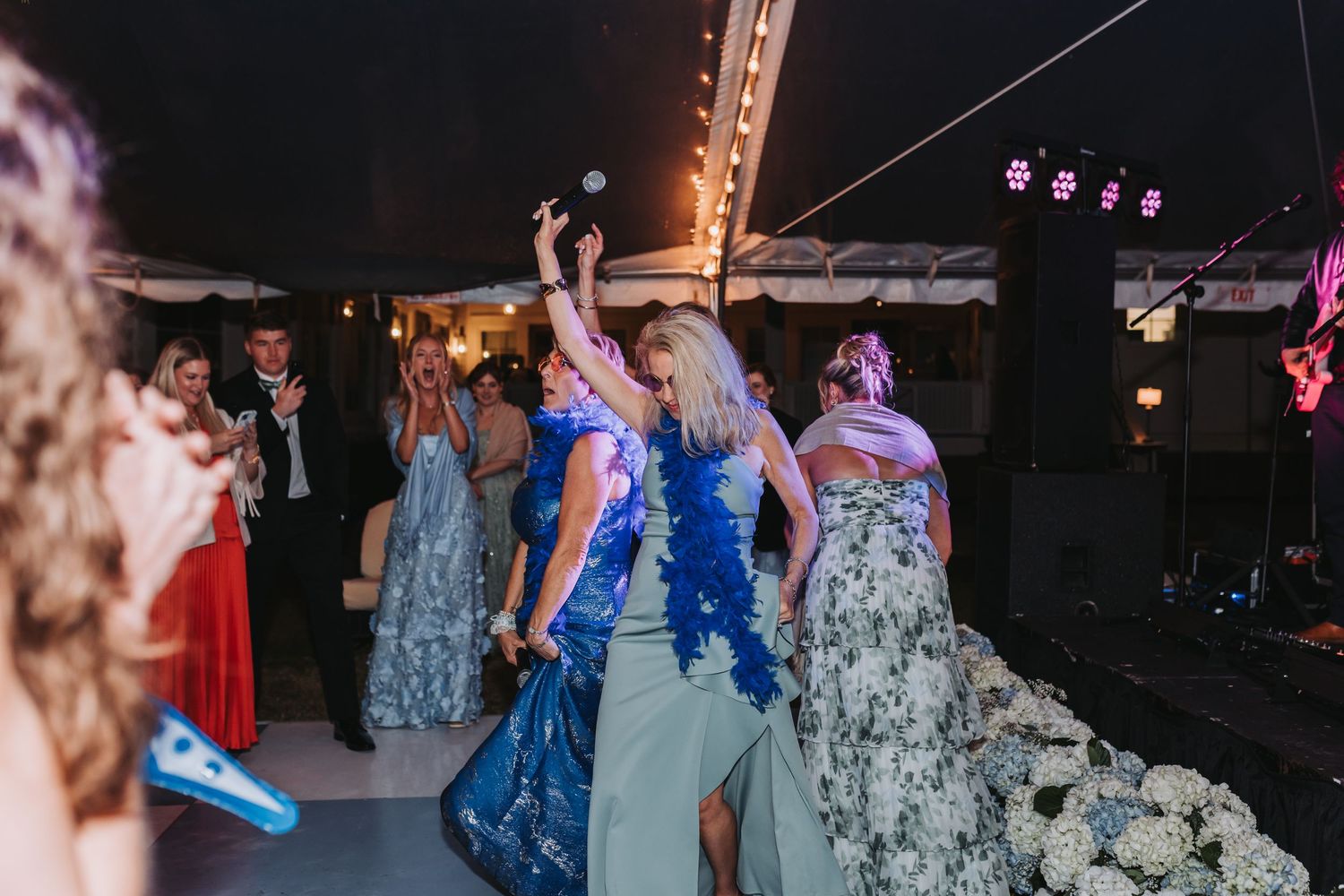 Wedding guests in formal attire dancing and celebrating at an outdoor tented reception.