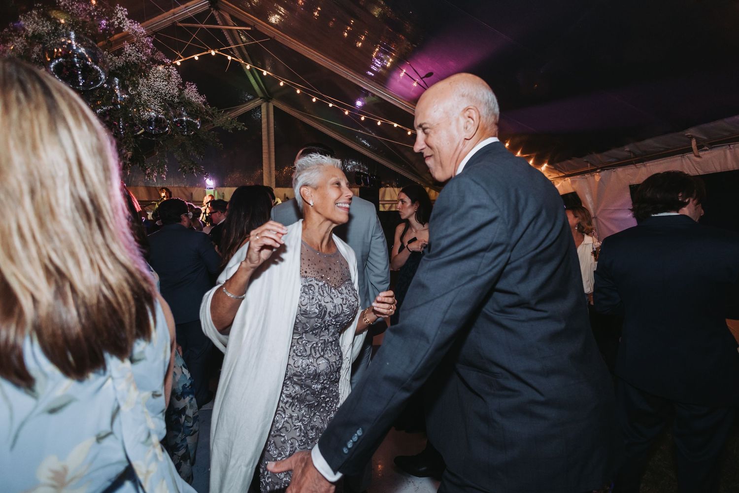 Elderly couple shares a joyful dance together at an elegant indoor wedding reception celebration.