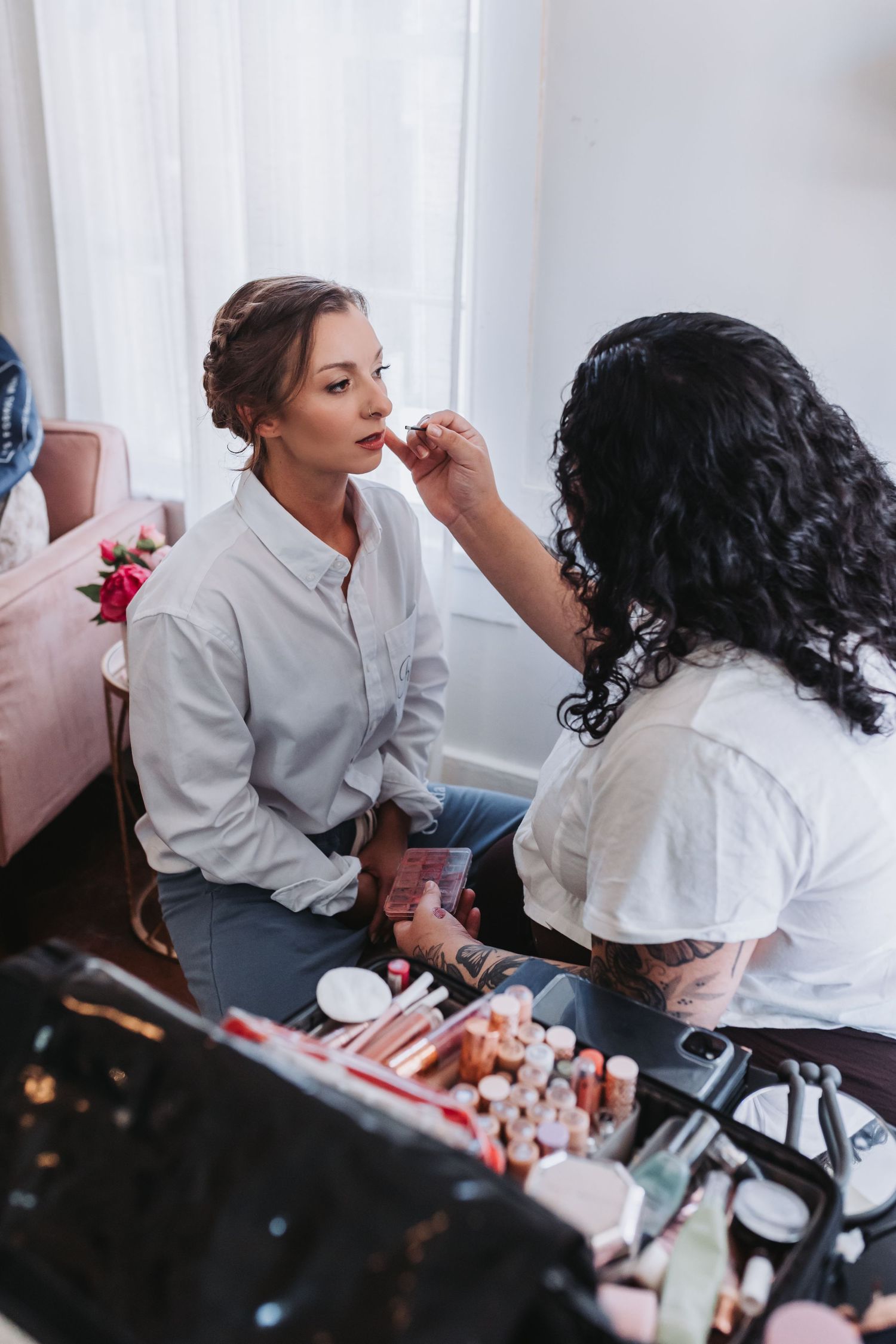 Makeup artist applying lipstick to a bride during wedding day preparations.