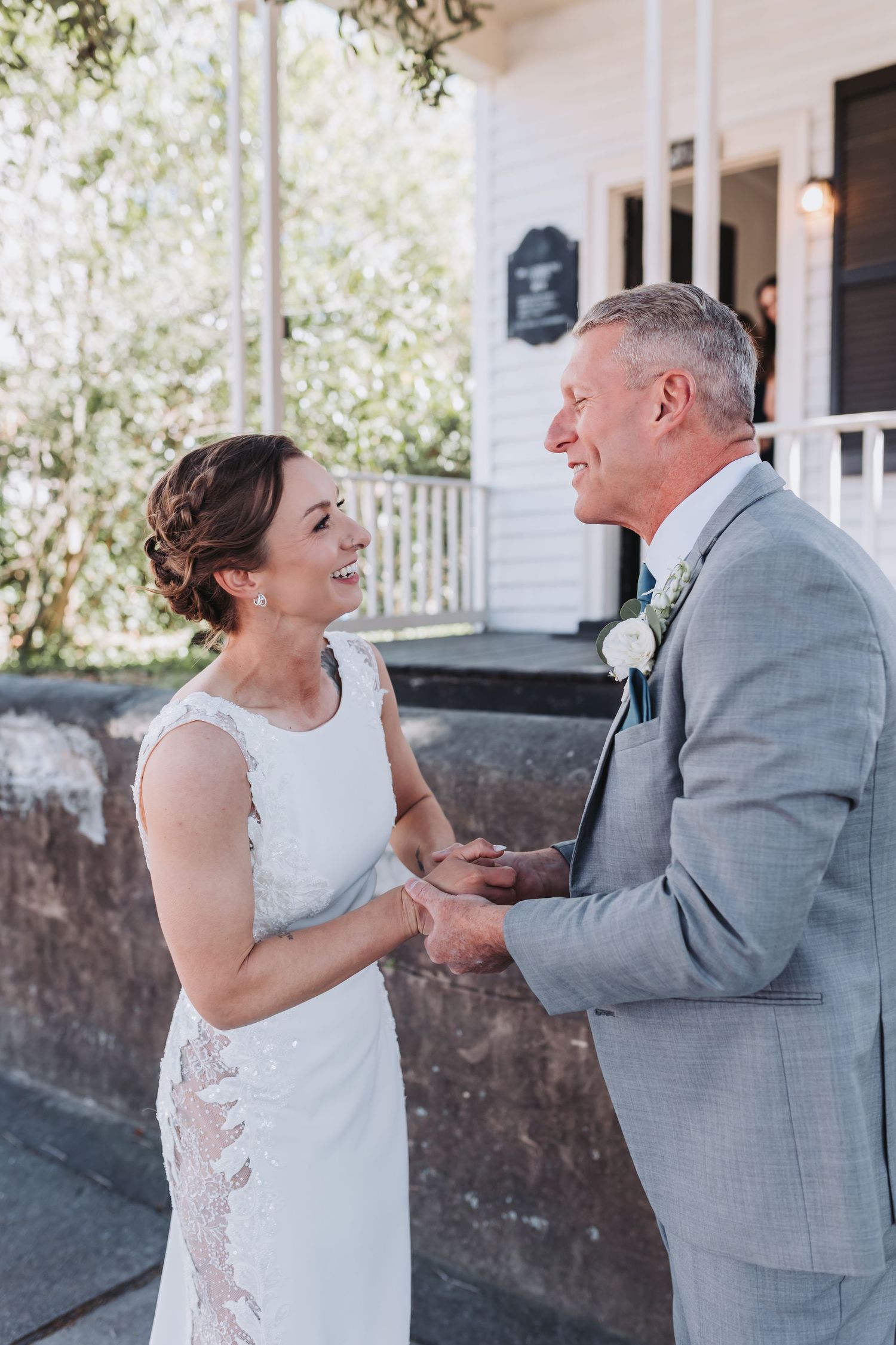 Bride and groom share a joyful first look moment outside holding hands.