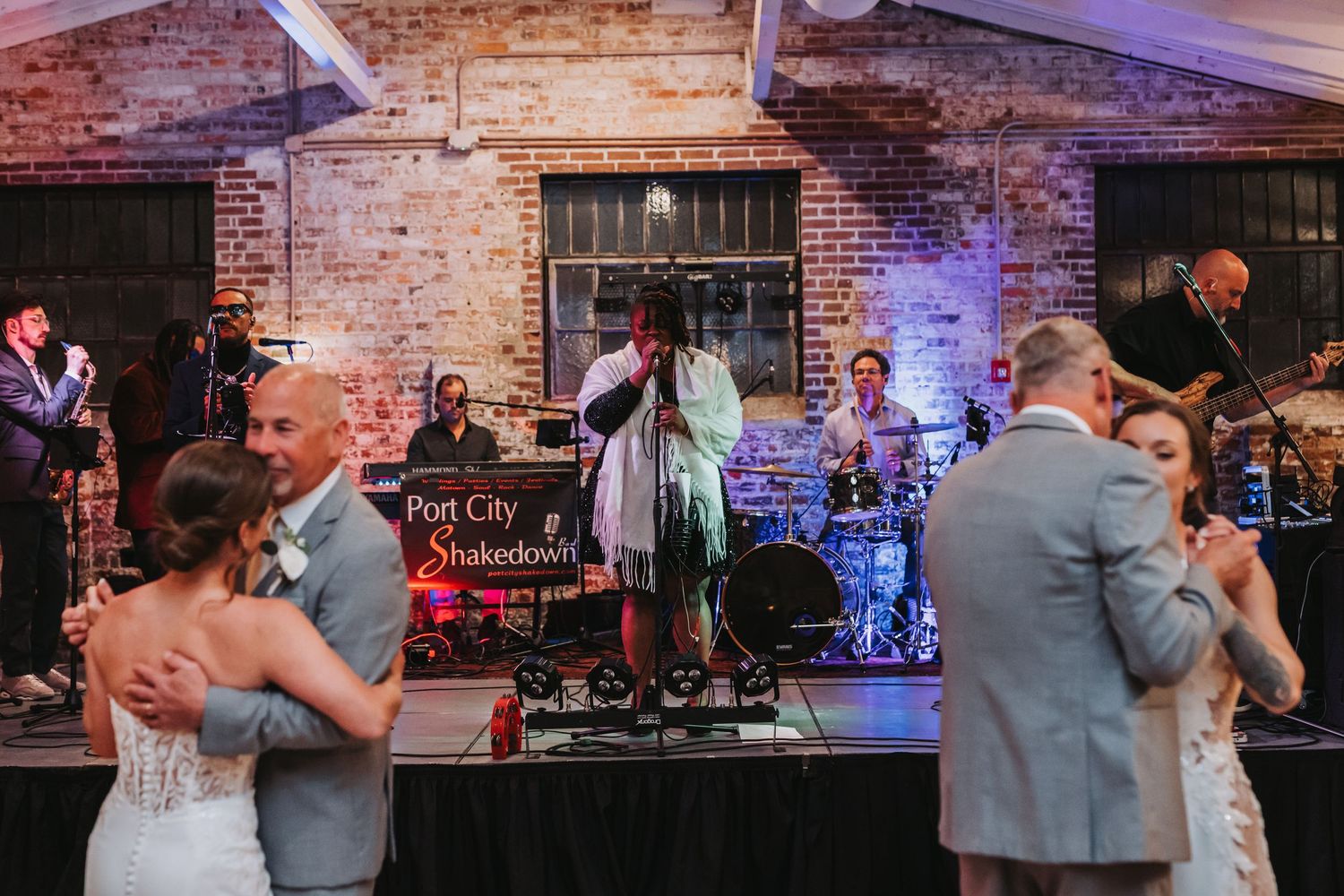 Two couples dancing on wooden floor with Port City Shakedown live band performing at wedding.