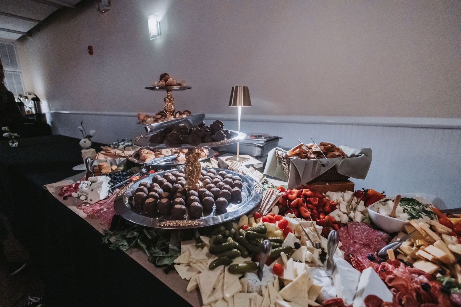 Elegant buffet table with chocolate truffles, fresh strawberries, and assorted cheeses at a catered event.