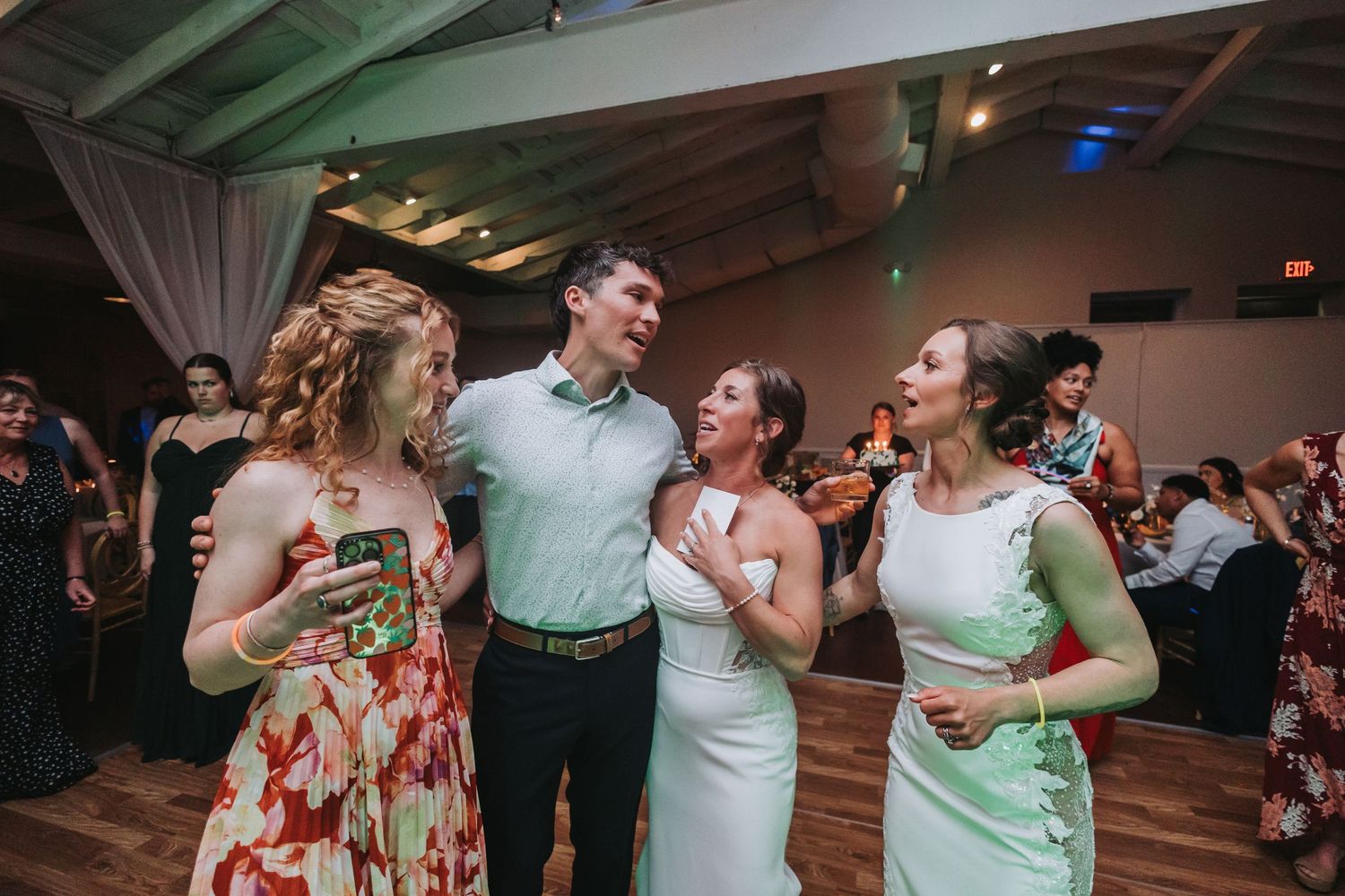 Guests laughing and dancing together at a wedding reception in a decorated venue.