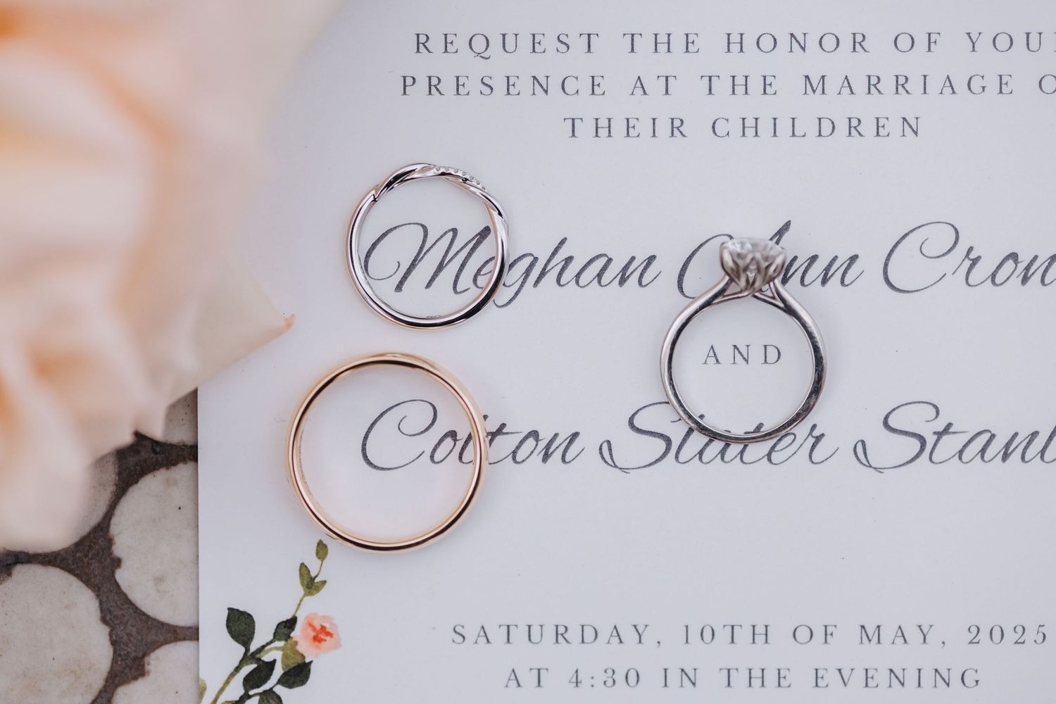 Wedding invitation for Meghan and Colton with two gold and silver rings resting on elegant stationery.