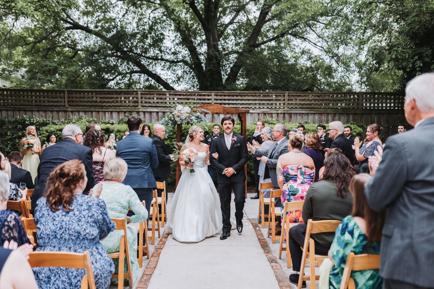 Newlyweds walk back down the aisle as husband and wife after outdoor garden wedding ceremony.