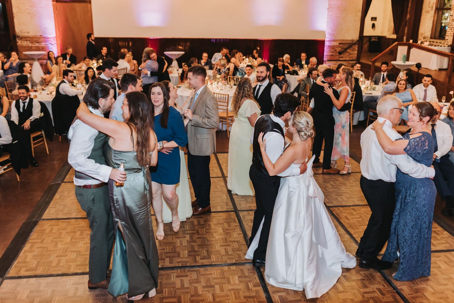 Guests and wedding party fill the dance floor during lively wedding reception celebration.