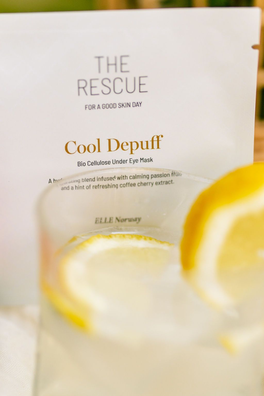 produit oslo skin lab cool depuff avec un verre d'eau et des lamelles de citron évoquant la fraîcheur de l'été