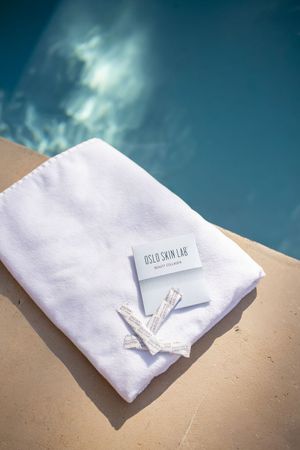 produits oslo skin lab disposés sur une serviette de bain au bord d'une piscine