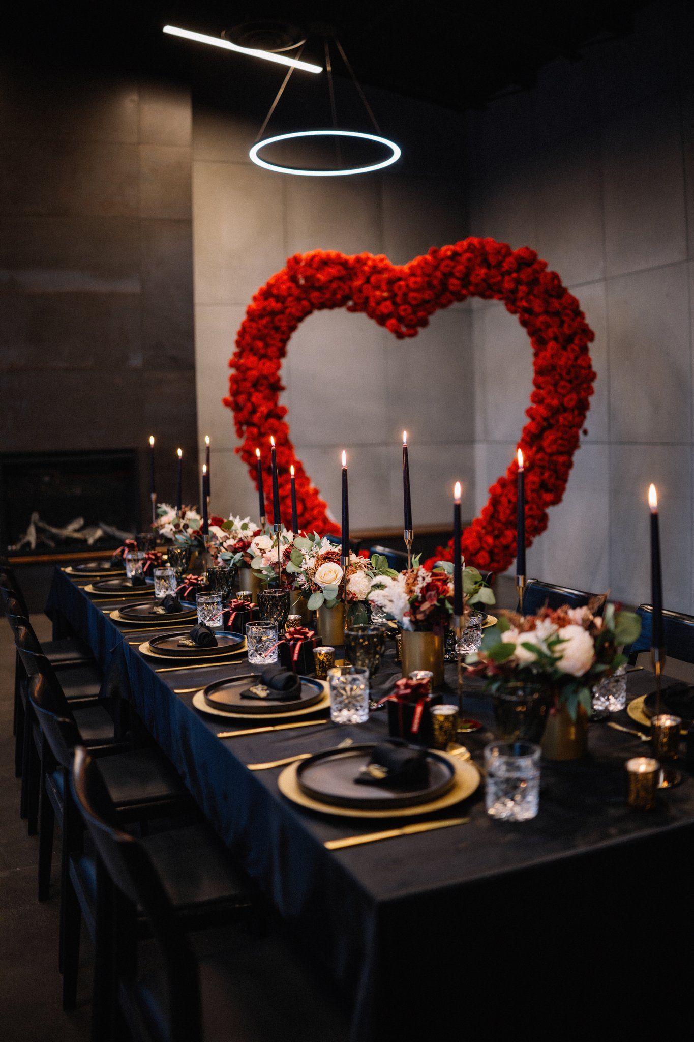 Giant red rose heart behind a moody candlelit reception table under a ring light at Mainspace Canmore