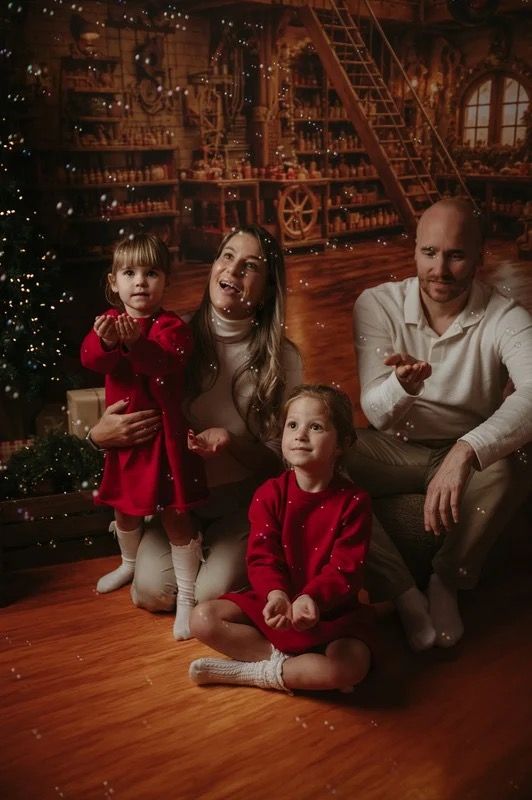 A family of four together in a warm Christmas setting, photographed during a previous session.