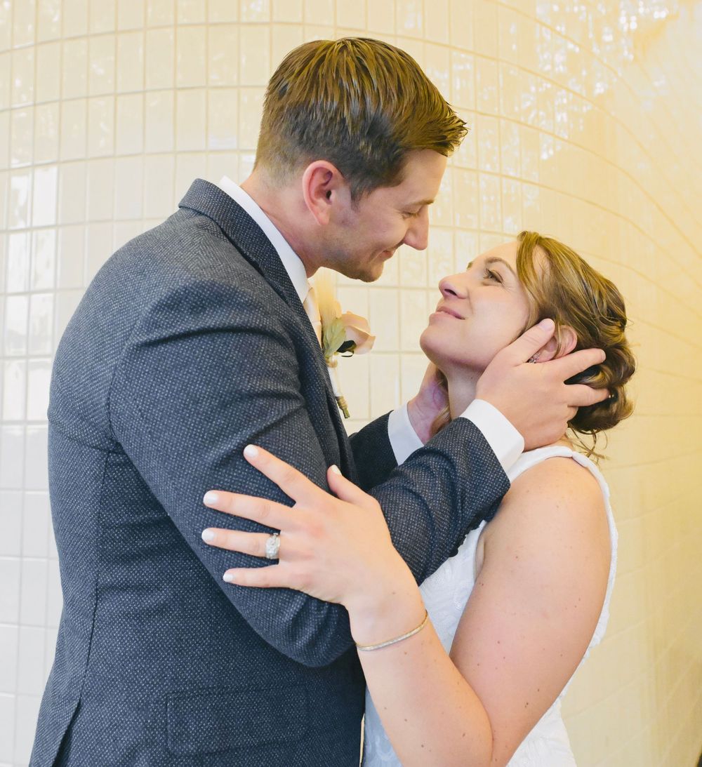 A bride and groom share a tender moment, with the groom gently holding the bride's face as they lean in for a kiss.