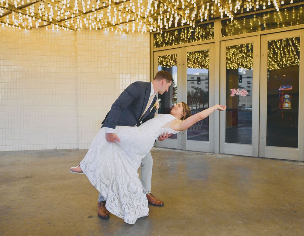 Bride and groom share a romantic dip dance under sparkling string lights at their wedding reception.