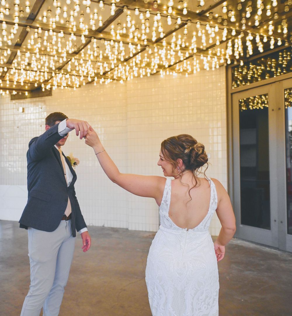 Bride and groom share first dance under sparkling Edison bulb ceiling at elegant wedding venue.