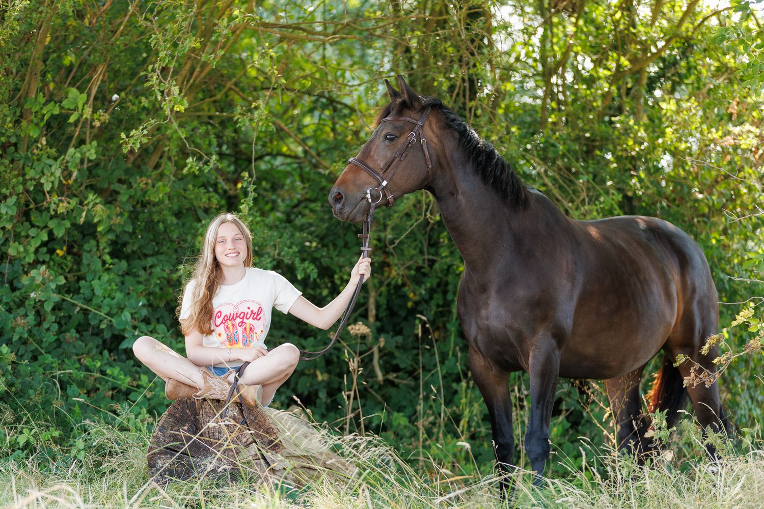 A horse and its rider enjoy an outdoor photoshoot session near rustic wooden fencing on a sunny day.