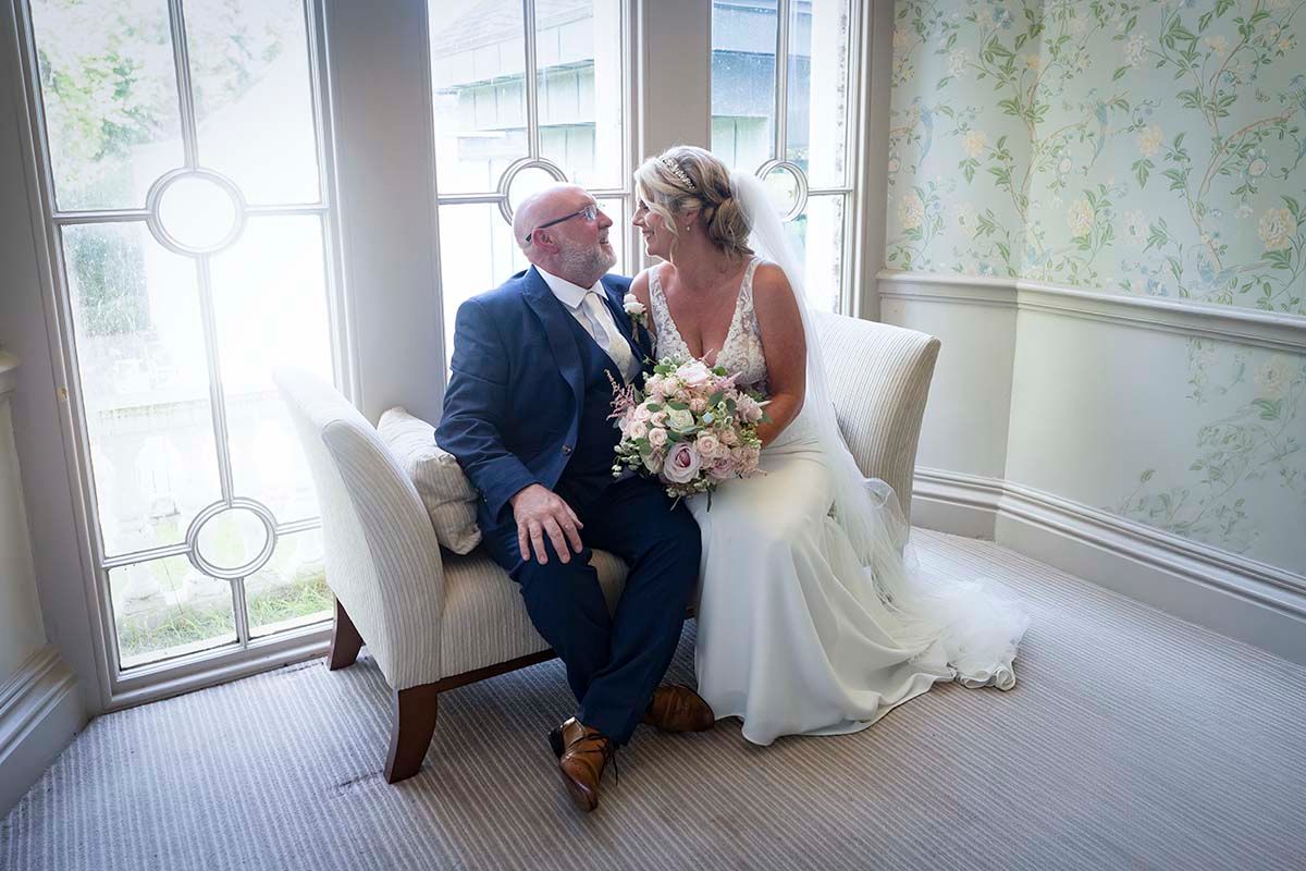Bride and groom share a romantic moment seated on the staircase at the Belsfield Hotel in Windermere