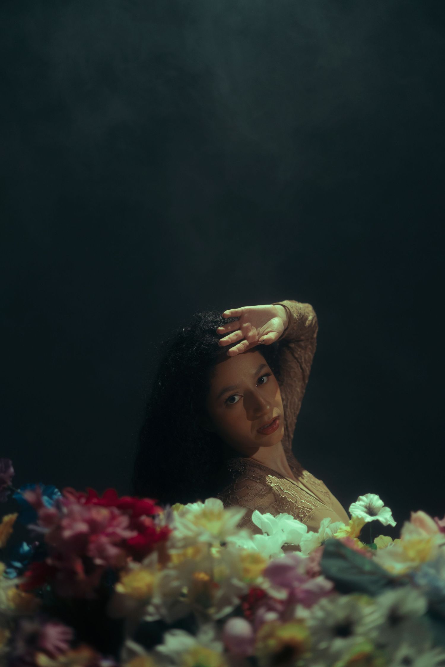 Woman rising from a bed of colorful flowers against a dark, smoky backdrop, Miami studio | Mannyportraits