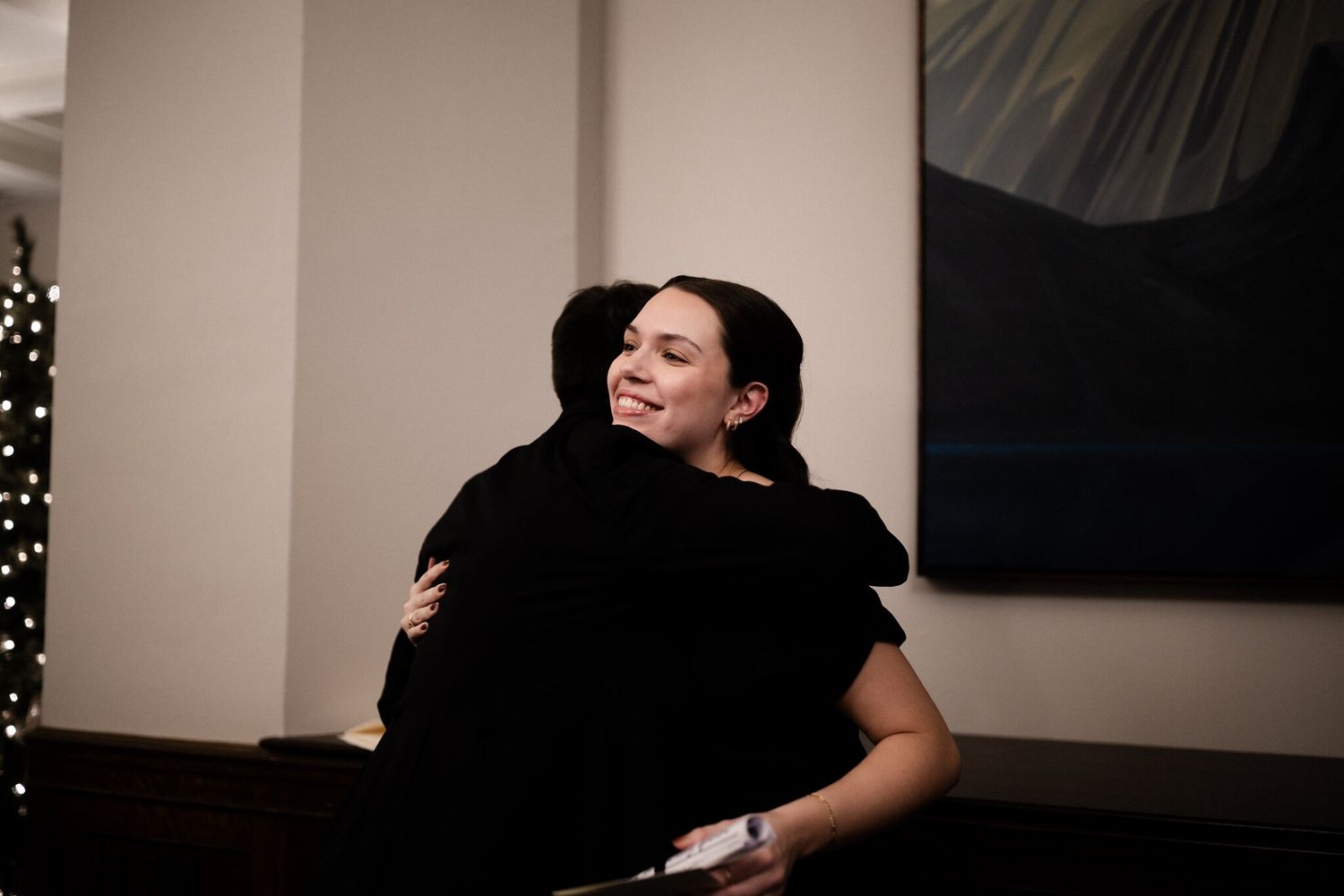 Smiling woman in a black dress shares a warm hug before the ceremony at a Fairmont Banff Springs Christmas wedding