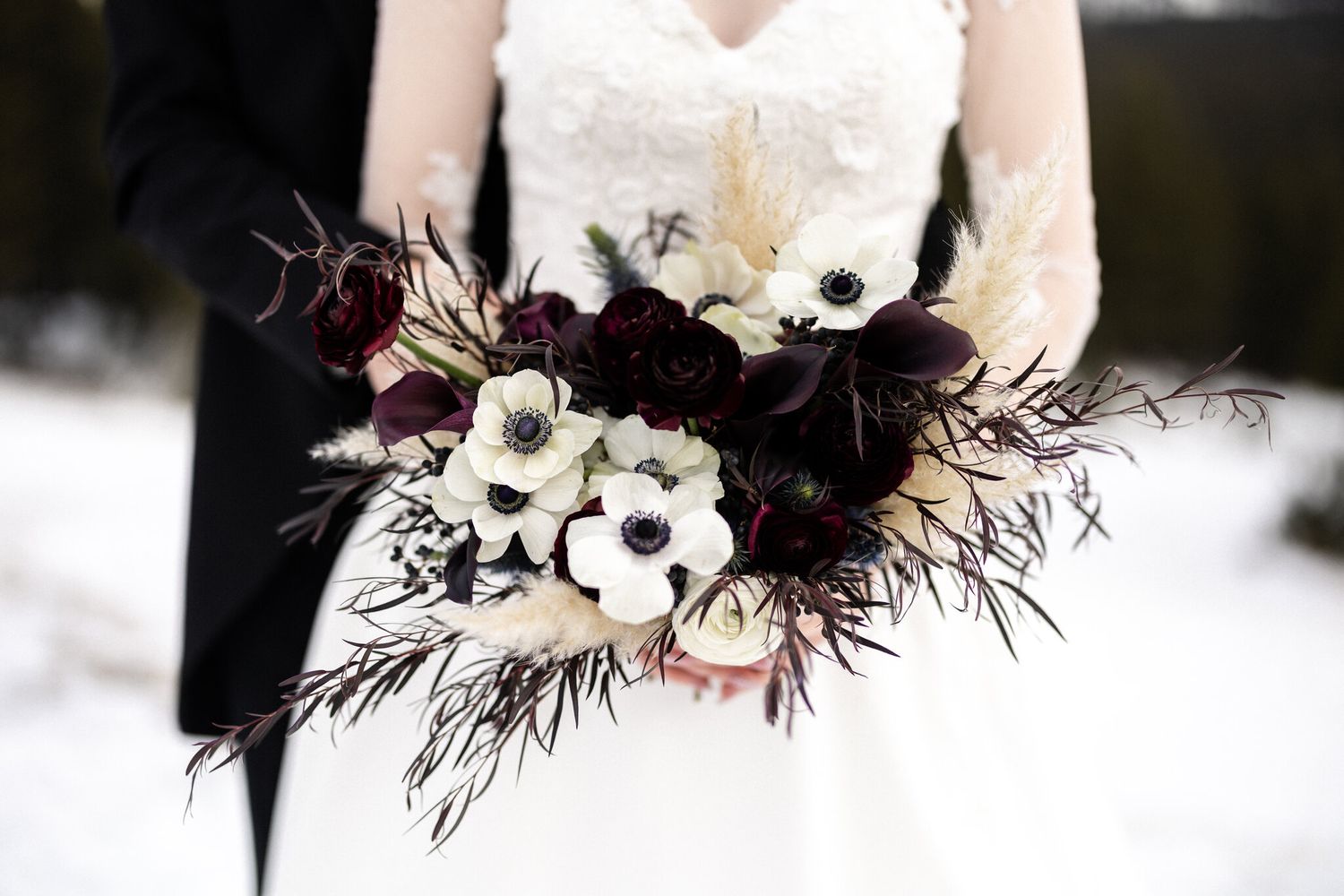 Bride holding an anemone and pampas bouquet in the snow at a Fairmont Banff Springs winter wedding