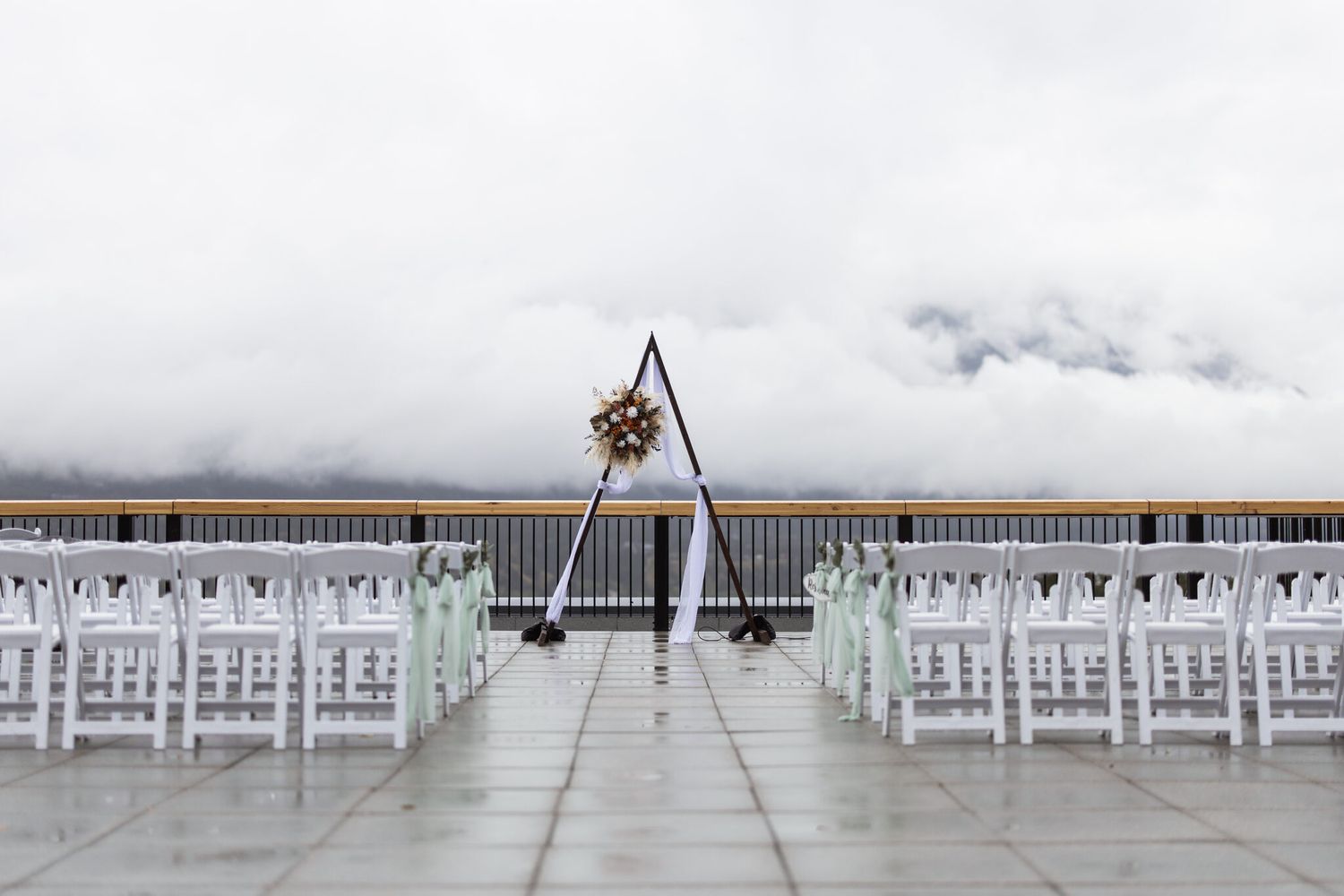 White ceremony chairs facing cloud-covered mountains at a Canmore wedding venue