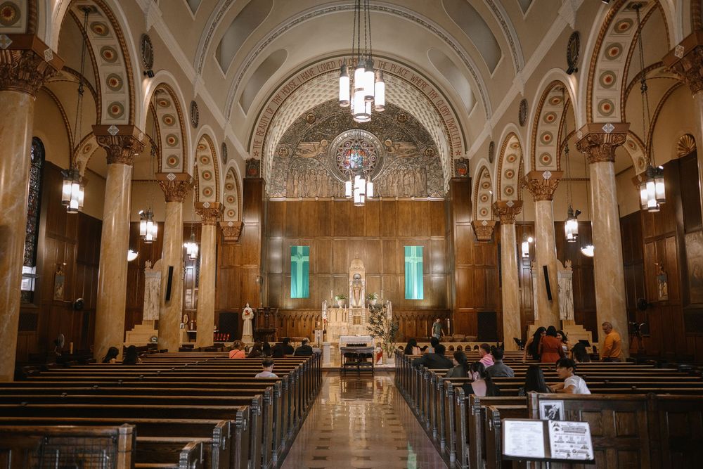 Grand cathedral interior with ornate arches, wooden pews, mosaic apse, and glowing altar under vaulted ceilings.
