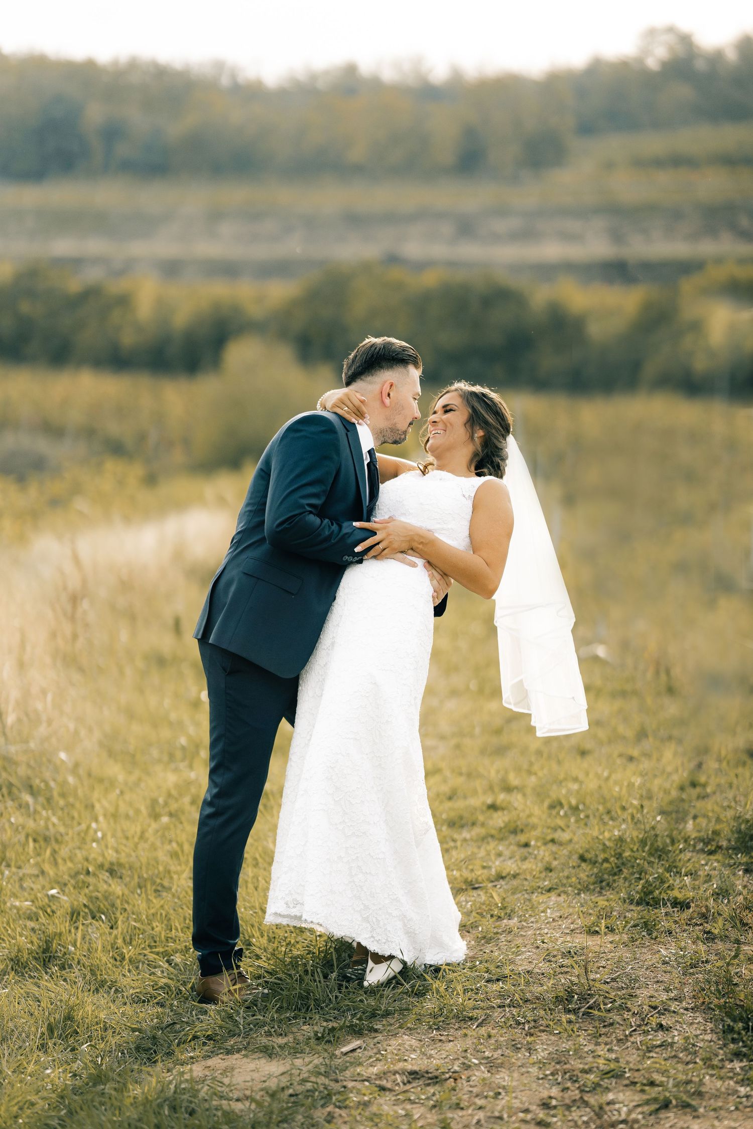 Egy esküvői ruhás pár romantikus pillanatot tölt meg egy festői őszi mezőn, a háttérben dombokkal.